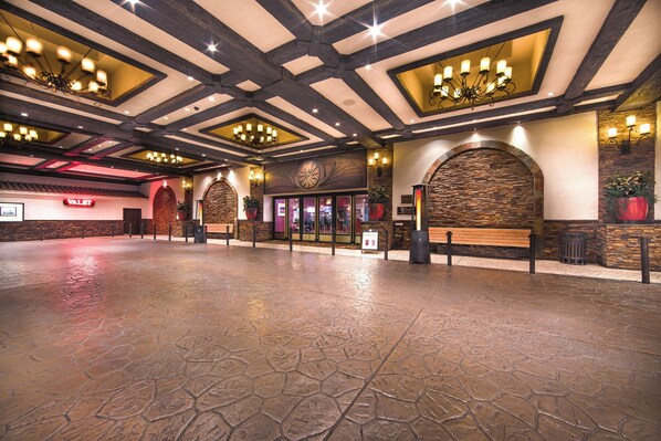 Eine geräumige Lobby mit Steinfußboden, Holzbalken und einem großen Chandelier.