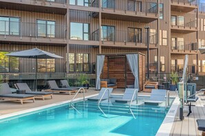 Ein Pool auf dem Dach mit Liegestühlen und einer Holzterrasse.
