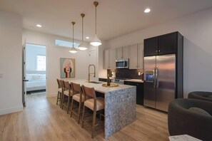 A modern kitchen with a central island, stainless steel appliances, and pendant lighting. - Double the Homes, Minutes from Broadway (Nashville)
