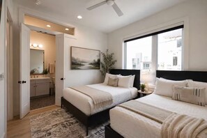 A hotel room with two beds, a large window, a painting, and a bathroom with a mirror and lights. - Double the Homes, Minutes from Broadway (Nashville)