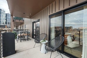 Ein Balkon mit Sitzgelegenheit, einem Tisch und Blick auf die Skyline.