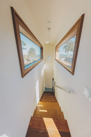 A narrow staircase with wooden steps and two large windows on either side. - Rooftop Oasis in Historic St. Augustine | Panoramic Intracoastal Waterway Views (St. Augustine)