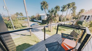 A balcony with a view of a residential street, a car, and palm trees. - Rooftop Oasis in Historic St. Augustine | Panoramic Intracoastal Waterway Views (St. Augustine)