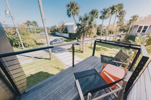 A balcony with a view of a residential street, a car, and palm trees. - Rooftop Oasis in Historic St. Augustine | Panoramic Intracoastal Waterway Views (St. Augustine)