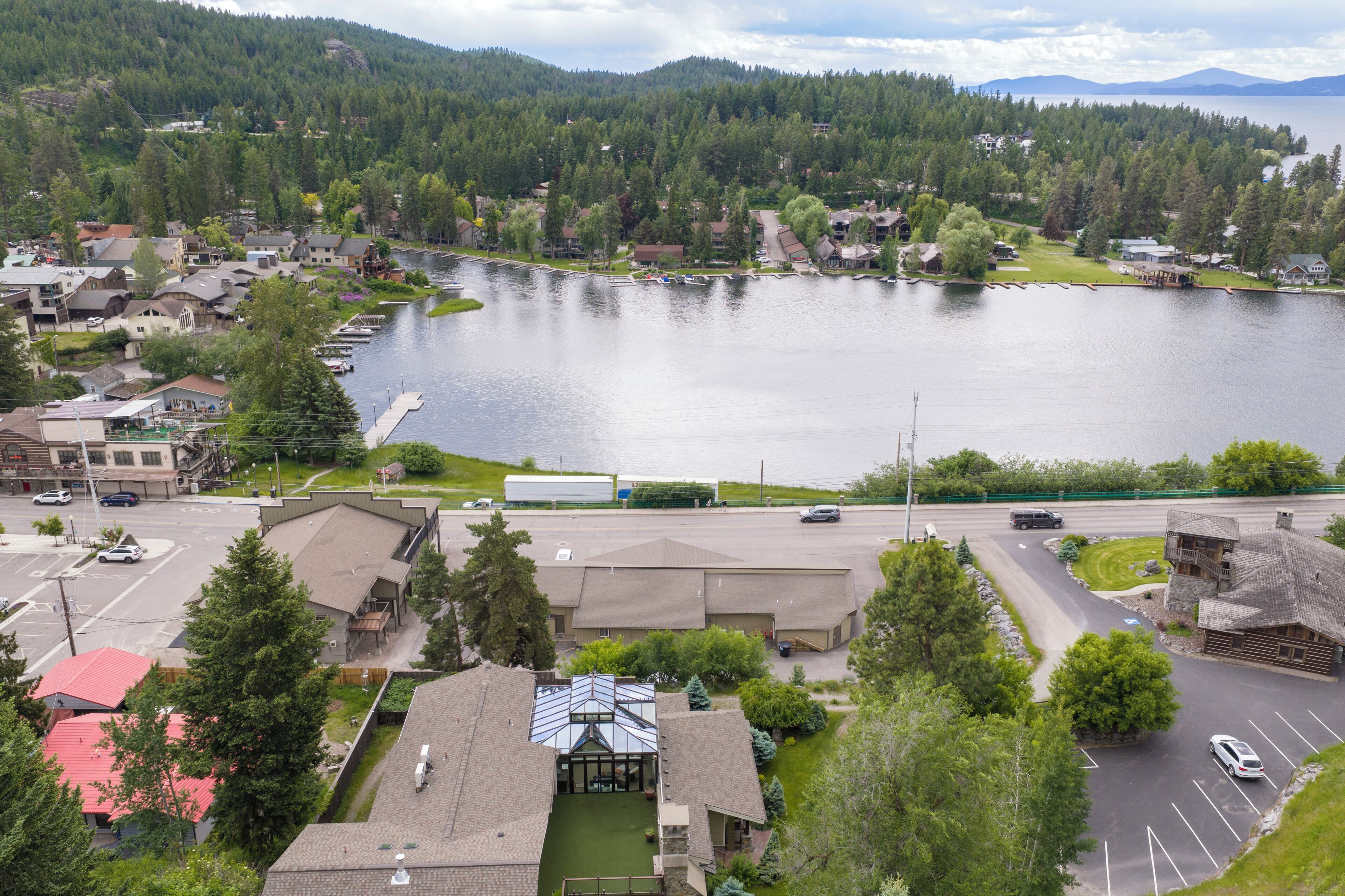 A lakeside town with residential buildings, a dock, and a parking area.