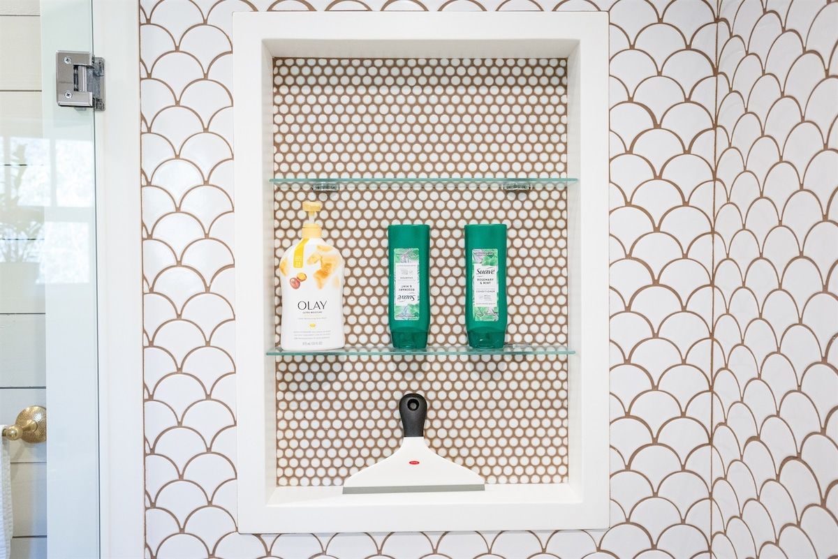 Ein Badezimmer mit einer Wand mit Muster, einer Glasablage für Toilettenartikel und einer weißen Tür mit goldener Griff.