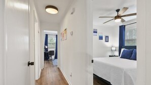 Une chambre d’hôtel équipée d’un lit, d’un ventilateur de plafond, d’un bureau avec une chaise et d’une fenêtre avec des stores.