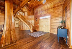 A wooden interior with a staircase, a door, and a small table with a decorative item. - The Ranch (6 Bedroom) (Royal)