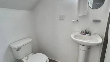 A small, white bathroom with a toilet, sink, and a window.