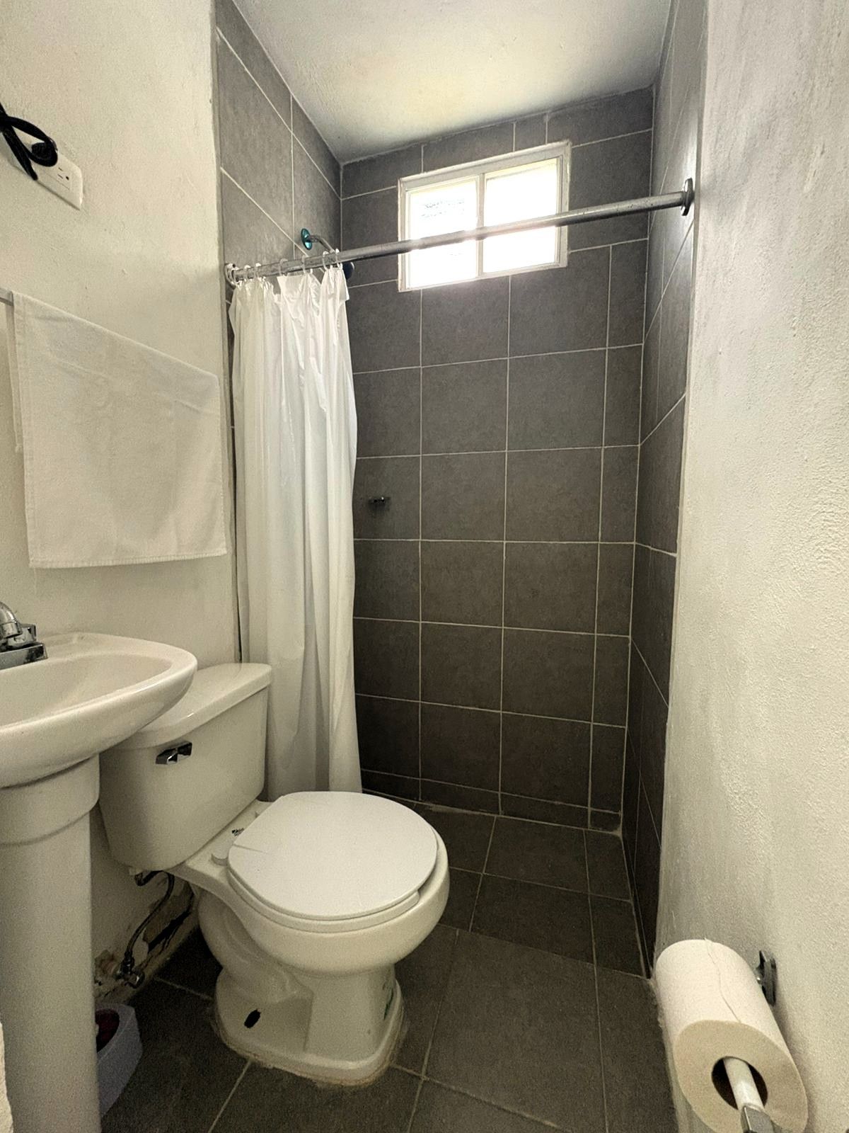 Une petite salle de bain avec des toilettes, un lavabo et un rideau de douche.