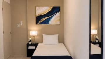 Quarto de hotel com cama, mesas de cabeceira, ventoinha no teto, espelho fixado na parede e um quadro.
