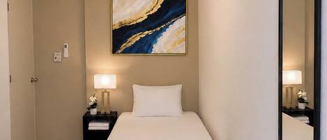 A hotel room with a bed, nightstands, a ceiling fan, a wall-mounted mirror, and a painting.