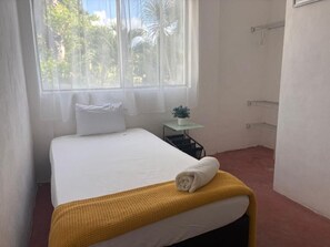 A hotel room with a bed, a small table with a plant, and a window with curtains. - Casa Balam Cayo Lobo (Cancún)