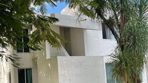 Um edifício moderno com fachada plana, janelas amplas e uma varanda visível.
