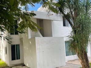 A modern building with a flat facade, large windows, and a visible balcony. - Casa Balam Cayo Lobo (Cancún)