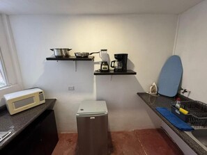 A compact kitchen with a microwave, a small refrigerator, a coffee maker, and a blender on a black countertop.
