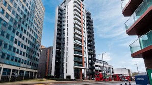 A multi-story building with a modern architectural design, featuring a prominent vertical stripe and balconies. - Spacious Woolwich Apartment with sea view (London)