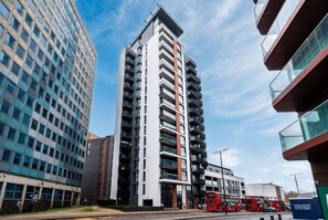 A multi-story building with a modern architectural design, featuring a prominent vertical stripe and balconies. - Spacious Woolwich Apartment with sea view (London)