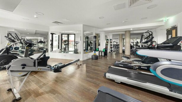 A gym with cardio machines, weight equipment, and mirrors. - Spacious Woolwich Apartment with sea view (London)