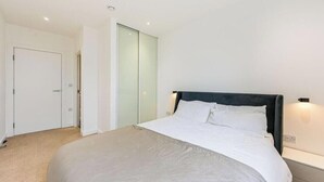 A bedroom with a bed, a nightstand, a door, and a closet. - Spacious Woolwich Apartment with sea view (London)