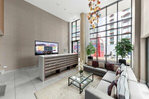 A modern lobby with a reception desk, a sofa, a coffee table, and large windows. - Spacious Woolwich Apartment with sea view (London)
