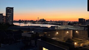 A cityscape at dusk with a river, buildings, and a bridge. - Spacious Woolwich Apartment with sea view (London)