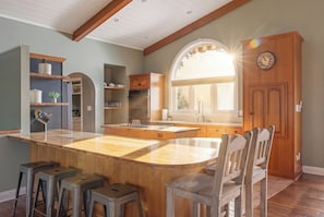A kitchen with a central island, wooden chairs, and a large window.