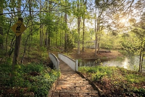 A wooden boardwalk leading to a gazebo by a lake, surrounded by trees.