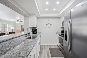 Eine moderne Küche mit Granit Arbeitsplatten, Edelstahlgeräten und einer zentralen Kochinsel.