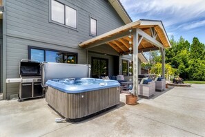 Eine Außenpatio mit Whirlpool, Grill und Sitzgelegenheit.