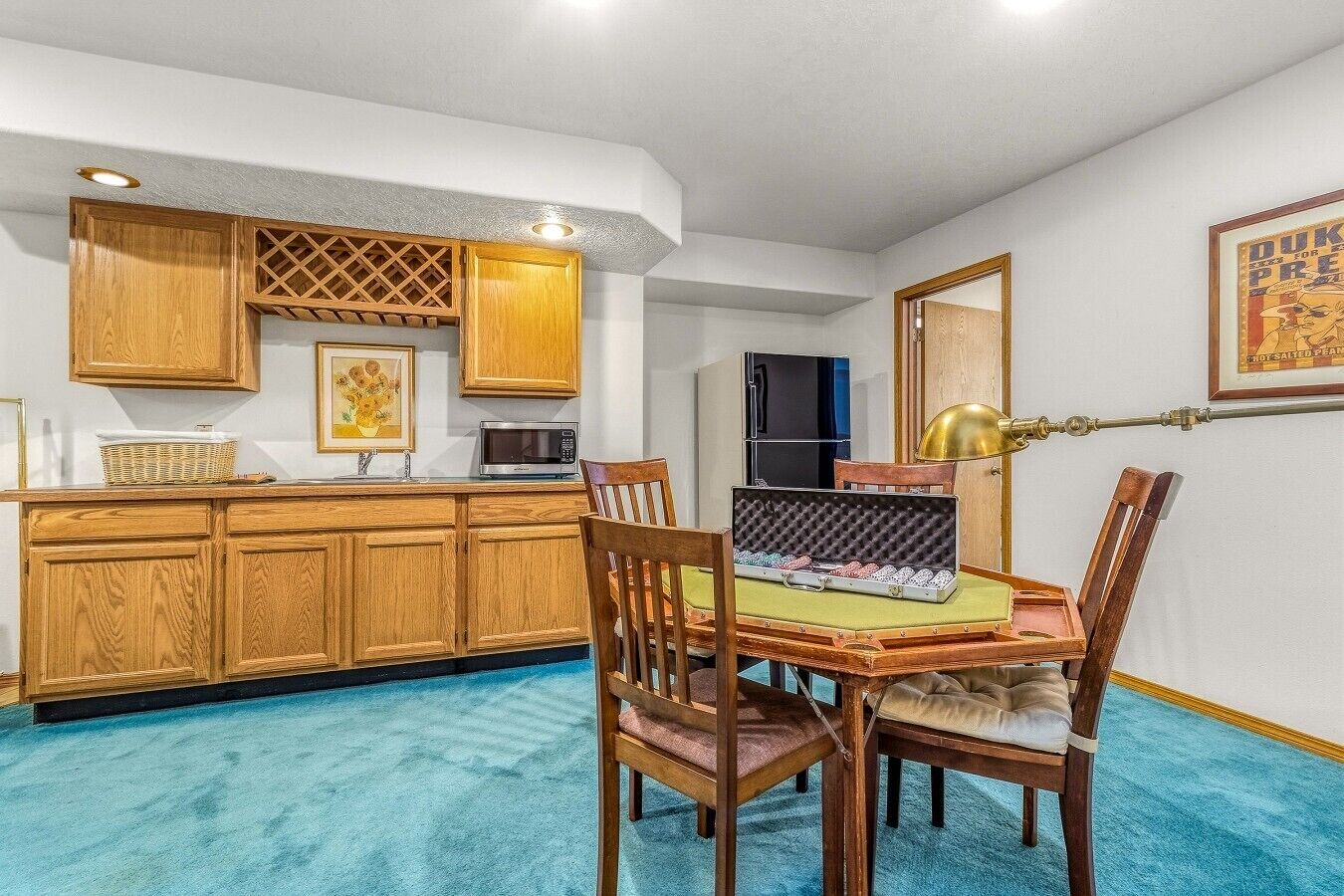Una cocina compacta con armarios de madera, un microondas y un comedor con mesa y sillas.