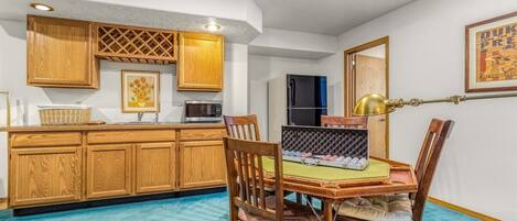 Una cocina compacta con armarios de madera, un microondas y un comedor con mesa y sillas.