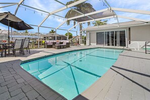 Une piscine dotée d’une structure en verre, de mobilier d’extérieur et d’un espace salon abrité.