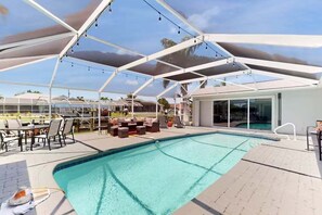 Ein Schwimmbecken mit Liegestühlen und einer überdachten Terrasse.