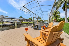 Une terrasse en bois dotée d’un espace salon couvert, donnant sur un port de plaisance.