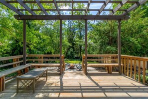 A wooden deck with benches and a pergola structure, surrounded by lush greenery. - The Reserve Extended Stay (Walla Walla)
