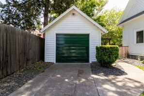 A single-story building with a green garage door, a wooden fence, and a well-maintained hedge. - The Reserve Extended Stay (Walla Walla)