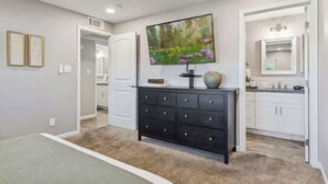 Un intérieur moderne avec une commode en bois foncé, un téléviseur à écran plat et un grand miroir.