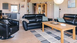 A cozy living room with a black leather sofa, a wooden coffee table, and a patterned rug. - 4 Star Holiday Home in Rudkobing (Rudkobing)