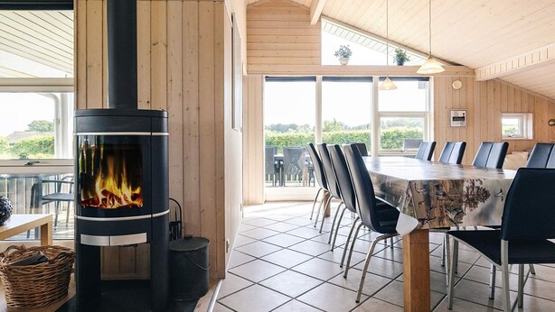 A modern wooden interior with a fireplace, dining area, and large windows. - 4 Star Holiday Home in Rudkobing (Rudkobing)