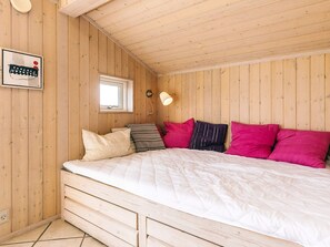 A room with a wooden sloped ceiling, a bed with white bedding, and a window with a view. - 4 Star Holiday Home in Rudkobing (Rudkobing)