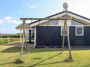 Uma casa residencial com fachada escura, antena parabólica e balanço no quintal.