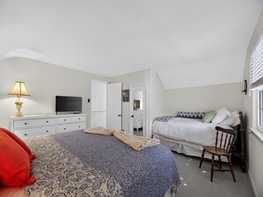Ein Schlafzimmer mit einem Bett, einem Sessel, einem Fernseher und einer Kommode.