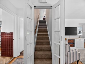 Eine Treppe führt zu einer Zwischenebene, im Hintergrund sind ein Fernseher und ein Stauraum erkennbar.