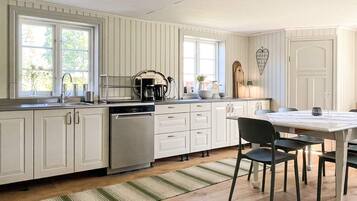 A kitchen with white cabinetry, a dishwasher, a coffee maker, and a dining table with chairs.