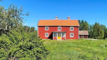 A red two-story house with a red roof, a yellow door, and a small porch.
