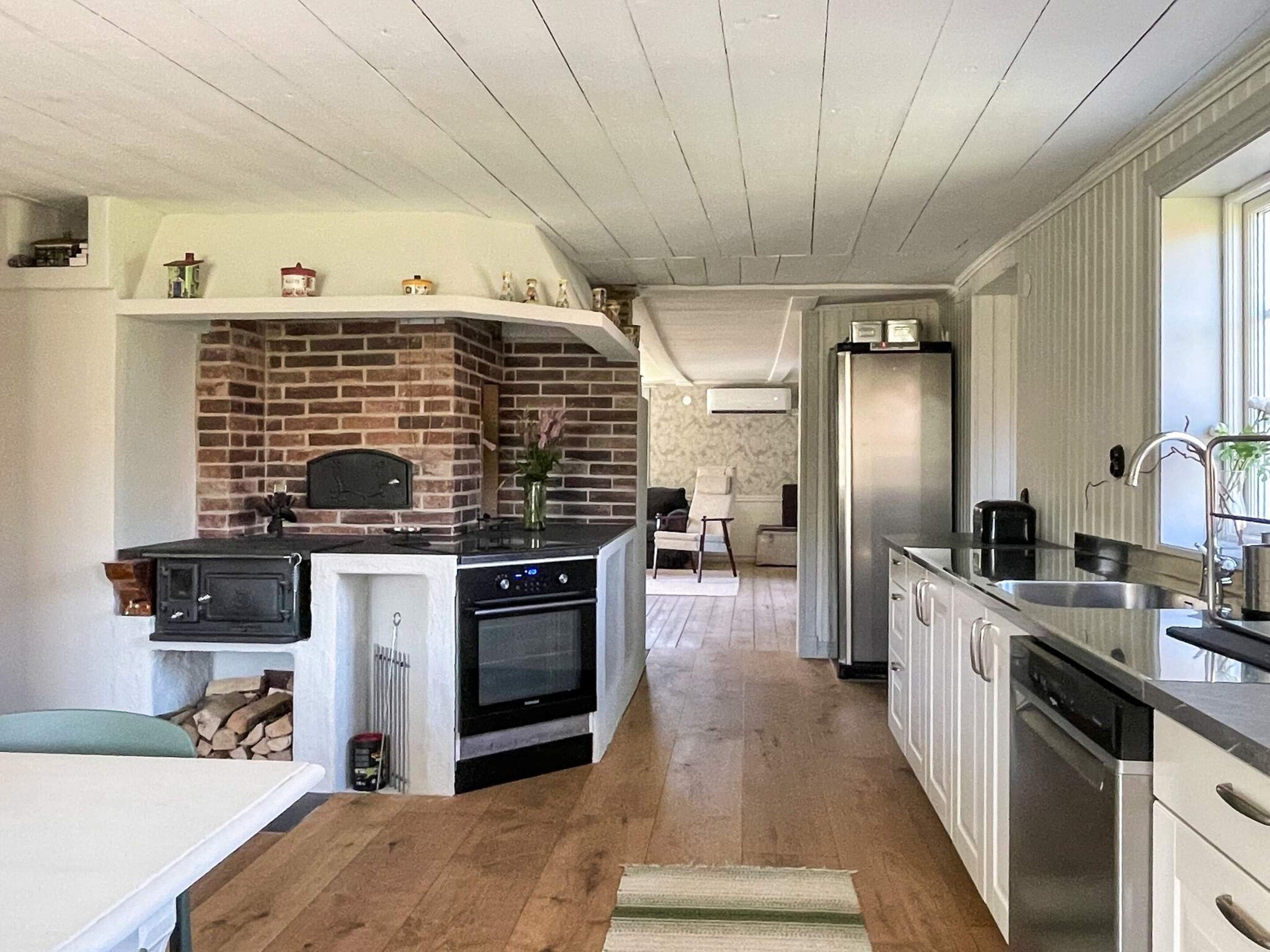 Una cocina moderna con chimenea de ladrillo, horno empotrado y electrodomésticos de acero inoxidable.