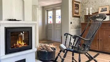 Una sala de estar con chimenea, un sillón mecedora y una puerta que da a otra habitación.