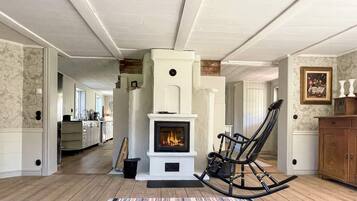 A room with a fireplace, a rocking chair, and a striped rug.