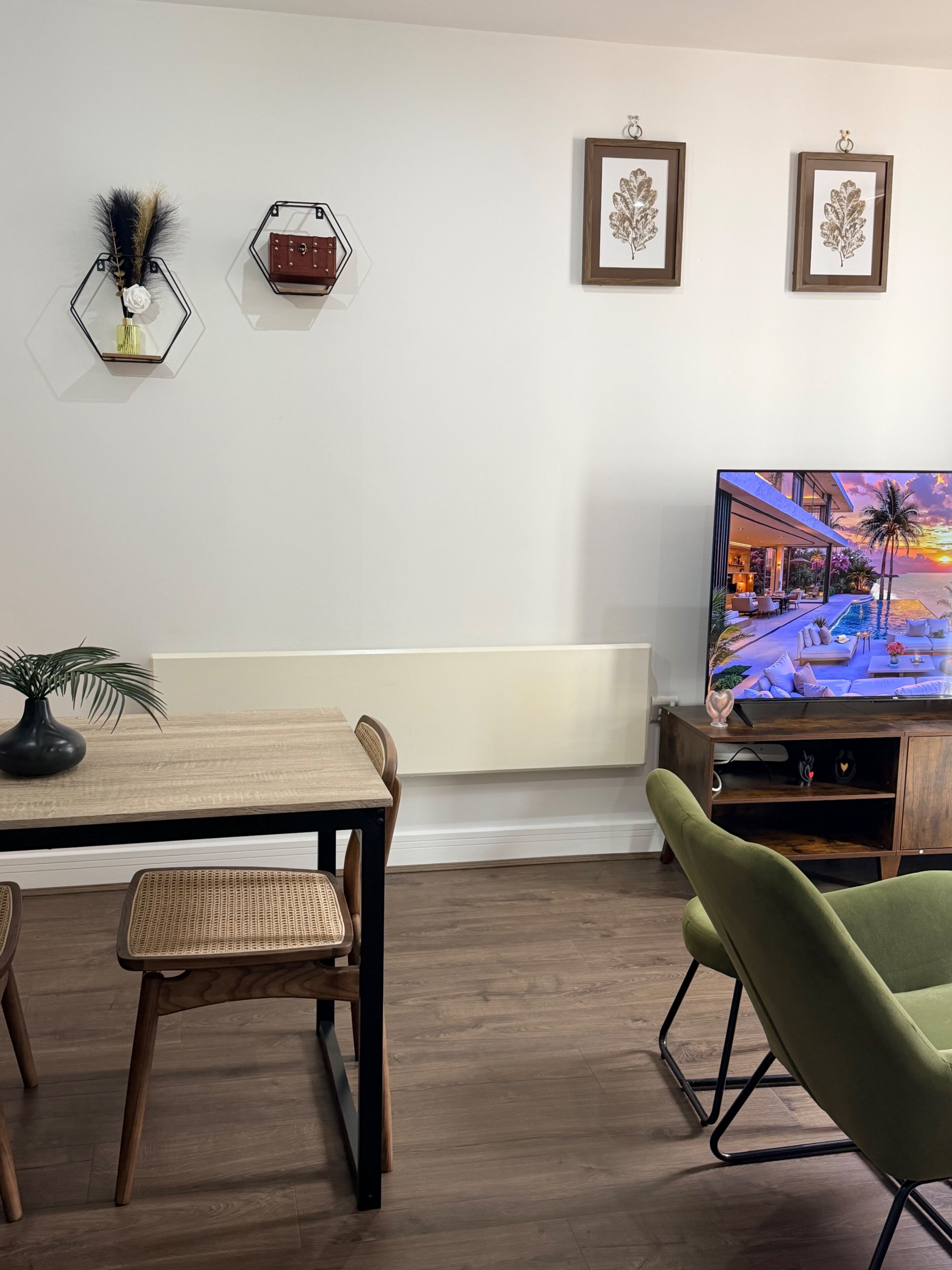 A modern living room with a dining table, chairs, a TV, and decorative wall art.